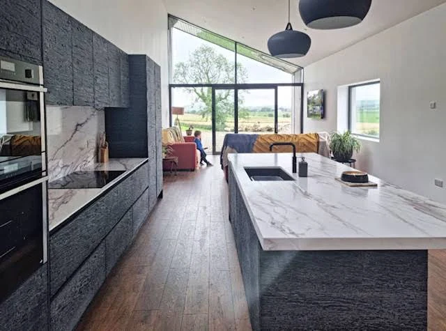 Textured burnt ash cabinetry and pale quartz island in Carrigans